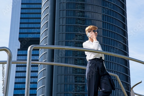 Businesswoman talks on the phone in front of a skyscraper