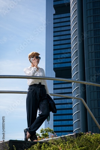 Businesswoman talks on the phone in front of a corporate building