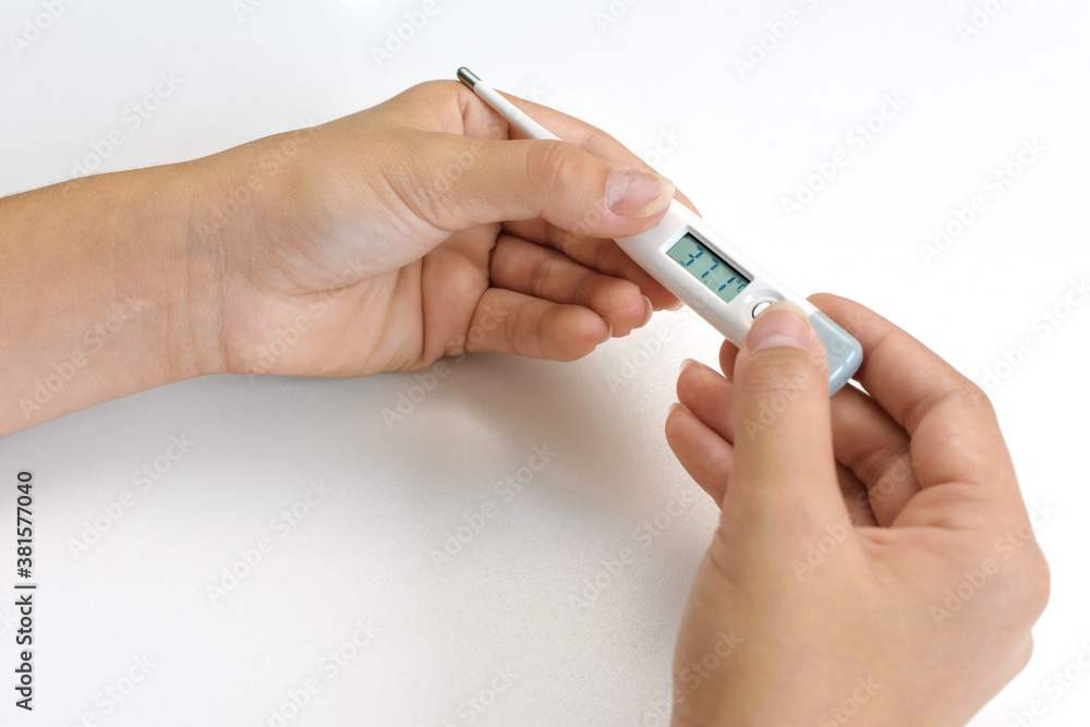 Woman hands holding white digital medical thermometer with high temperature - close up view. Healthcare, measurement, disease, infection, coronavirus concept Woman hands holding white digital medical thermometer with high temperature - close up view. Healthcare, measurement, disease, infection, coronavirus concept