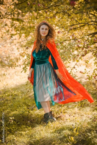 Woman in green velvet romantic dress and red hood, Halloween style for girls, autumn nature at background