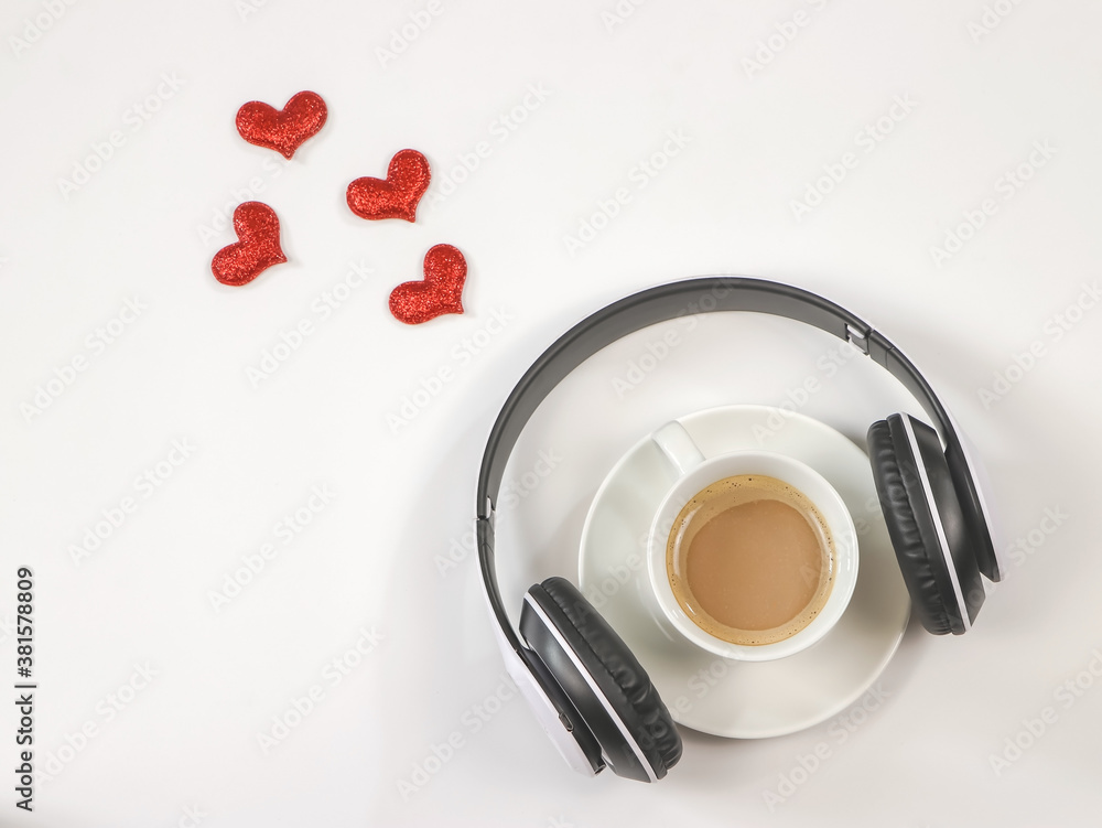 Flat lay of coffee cup cover with headphones on white background with red glitter hearts decoration. Love song ,Music and coffee relaxing time concept.