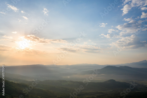 Early morning in the mountains. Morning sun and haze in the valley against the background of mountains. Mountain summer landscape