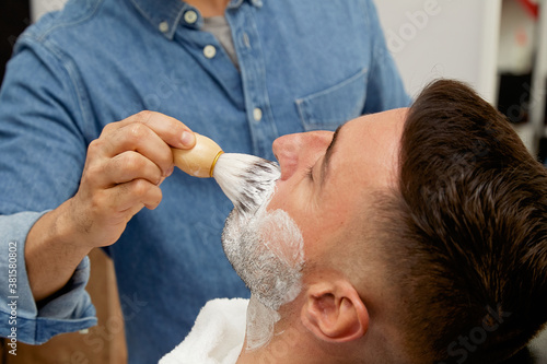 Barber preparing client to shave beard