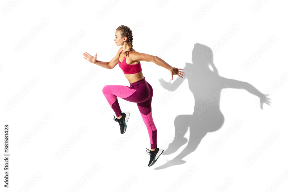 Dancing. Beautiful young female athlete practicing on white studio background, portrait with shadows. Sportive fit model in motion and action. Body building, healthy lifestyle, style concept.