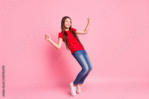 Full body size photo of lovely sweet little lady long hairstyle performance dance raise hand finger toothy smile tiptoe wear casual red t-shirt jeans sneakers isolated pink color background © deagreez
