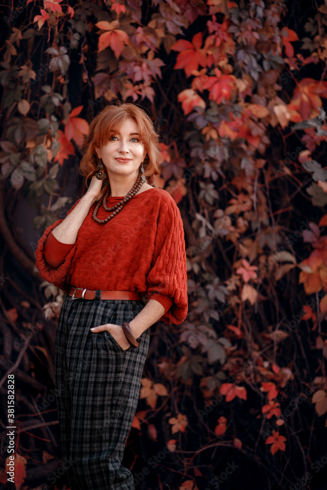 Autumn portrait of a beautiful  red-haired woman on the wild grape background