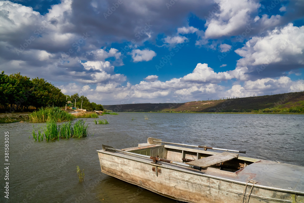 Old metal fishing boat moored in the shallow waters of the river