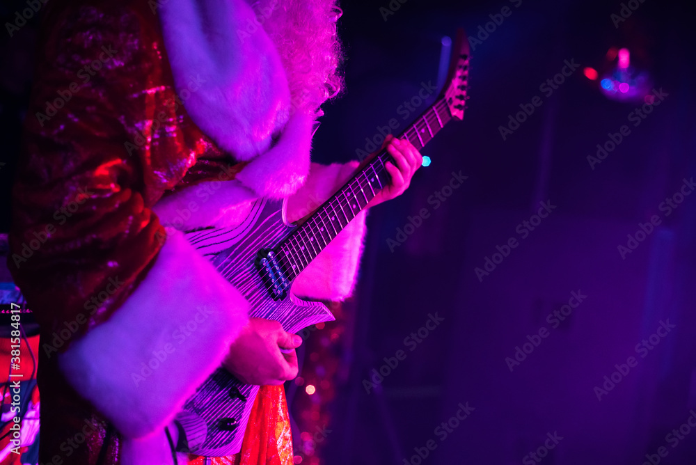 Obraz premium guitar in the hands of a man dressed up in a Christmas Santa Claus costume