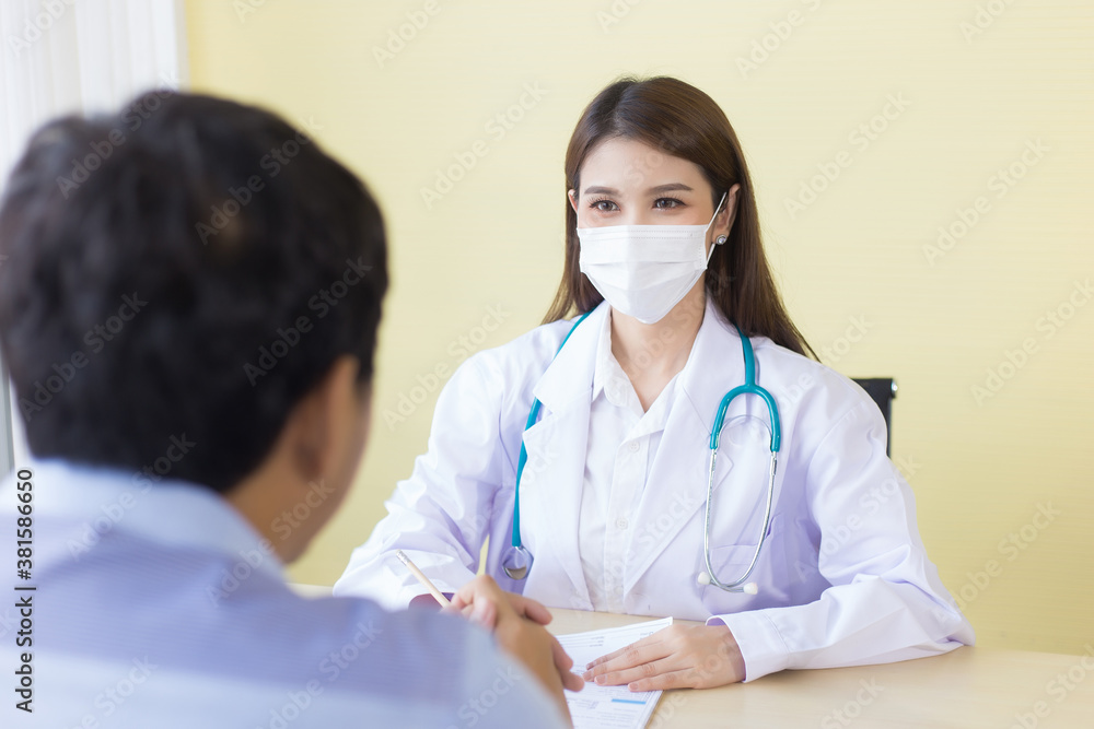 Asian female doctor. Asking patient questions. By wearing a surgical mask at all times. Asian female doctor. Asking patient questions. By wearing a surgical mask at all times.