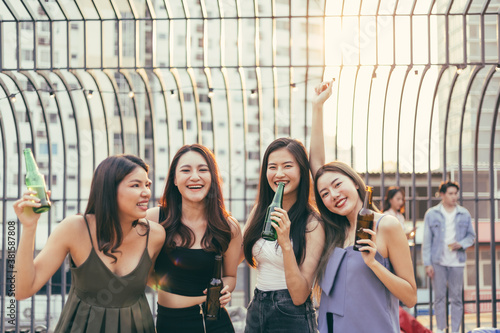 Group of Asian girl having party with hand holding beer bottle toasting at outdoor restaurant. drinking alcohol, young people night lifestyle. positive emotion and friendship concept. copy space © winnievinzence