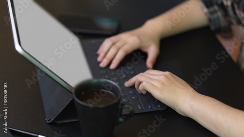 Female hands typing on tablet keyboard on black table