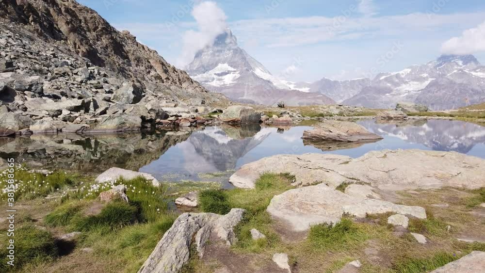 Alpine meadows around Riffelsee Lake with mirror of Mount Matterhorn and Swiss Alps. Zermatt, Canton of Valais, Switzerland. Riffelsee is located on Riffelseeweg trail on Gornergrat Bahn cog railway. Alpine meadows around Riffelsee Lake with mirror of Mount Matterhorn and Swiss Alps. Zermatt, Canton of Valais, Switzerland. Riffelsee is located on Riffelseeweg trail on Gornergrat Bahn cog railway.