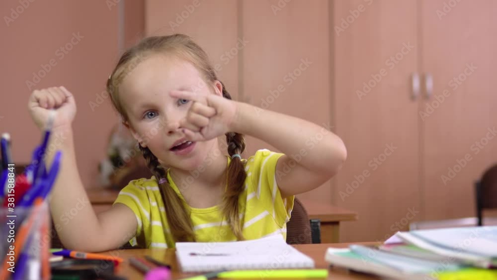 A beautiful little girl sits at the table and counts her fingers on her hand. Preschool education. 4k A beautiful little girl sits at the table and counts her fingers on her hand. Preschool education. 4k