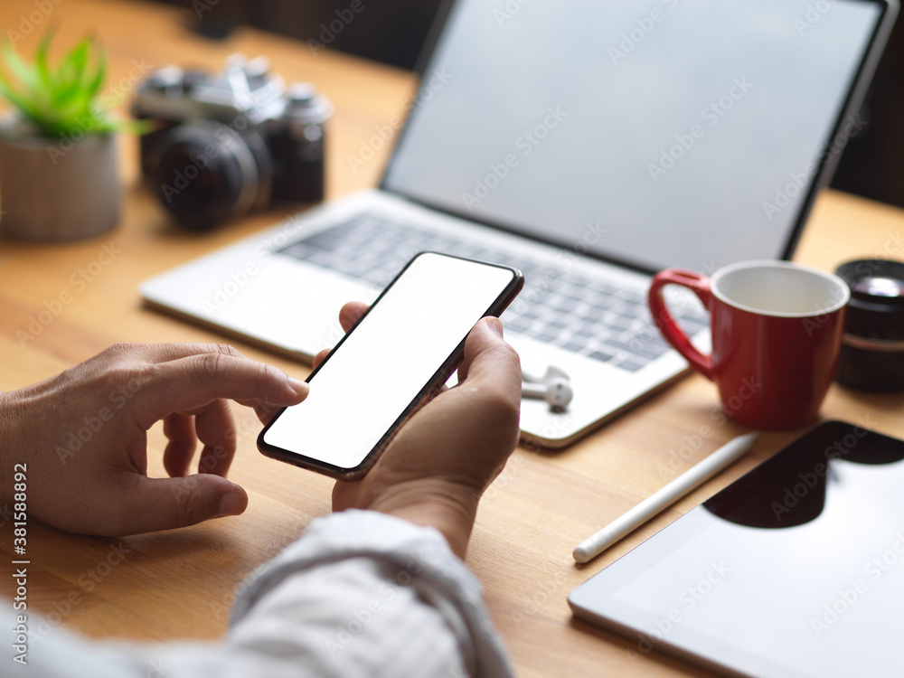 Male using mock up smartphone while working in office room Male using mock up smartphone while working in office room
