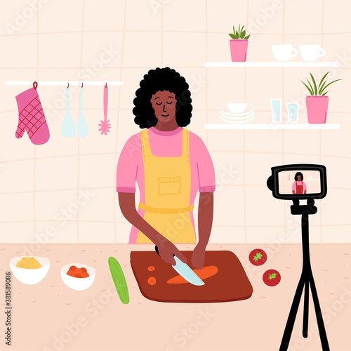 Black african Female chef cooking in the kitchen while recording video using her camera for her online video channel. food at home. homemade meals. culinary video blog or master. 
