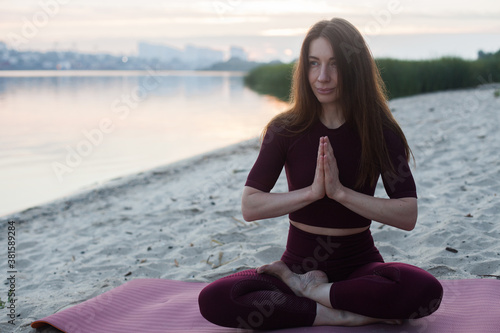Young woman doing Hatha yoga on the beach in the morning. Outdoor meditation