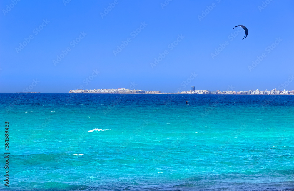 Kite surfing on the sea: on background Gallipoli skyline, Apulia (Italy), whose name means Beautiful City, rests like a mirage on the Ionian coast, roughly 40 km from Lecce.