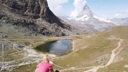 Mount Matterhorn reflected on Riffelsee Lake. Tourist woman relaxing after trekking from Rotenboden station on Gornergrat Bahn cog railway. Tourism in Zermatt, Canton of Valais, Switzerland. photo