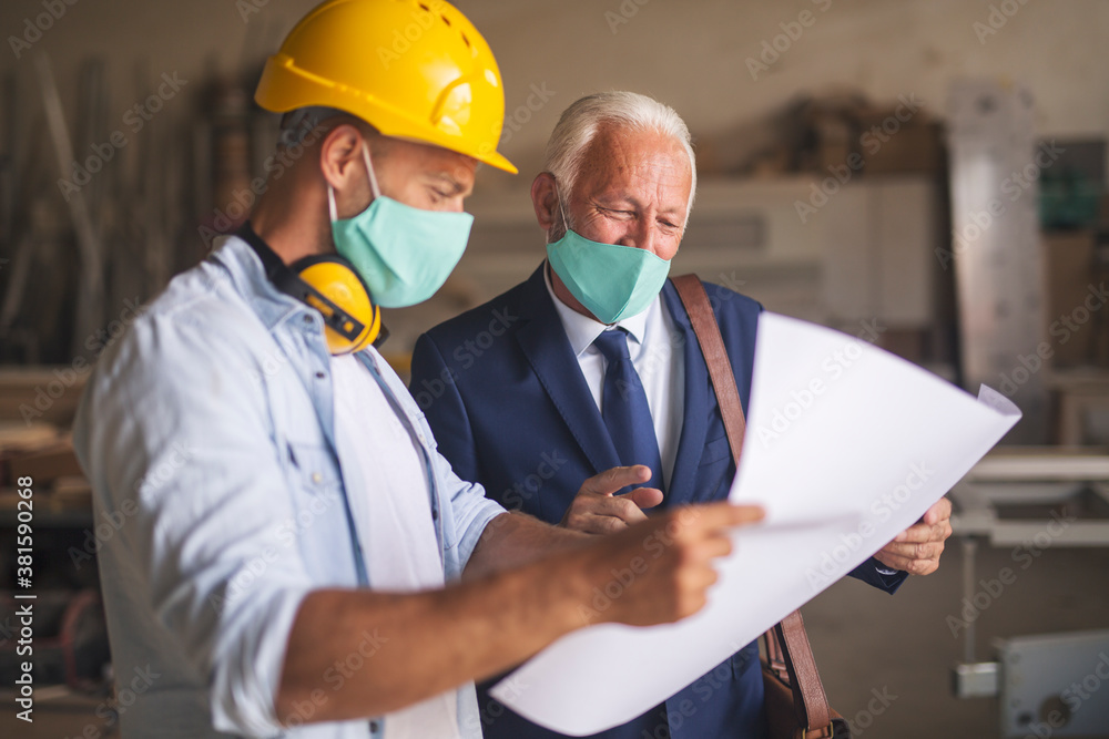 Woodworkers looking at project papers and smiling Woodworkers looking at project papers and smiling