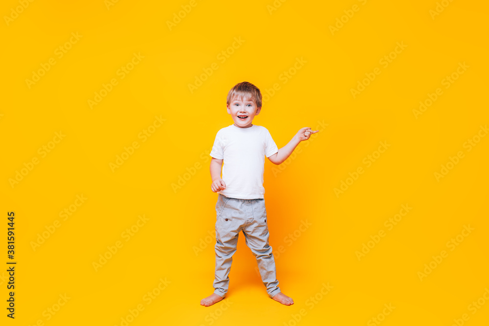 Cute boy on yellow background points with his hand to the side, photo for advertising product Cute boy on yellow background points with his hand to the side, photo for advertising product