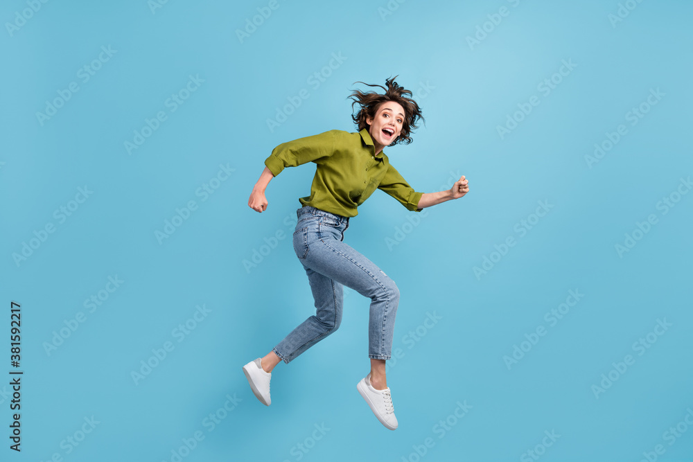 Photo portrait of woman running jumping up laughing isolated on pastel light blue colored background Photo portrait of woman running jumping up laughing isolated on pastel light blue colored background