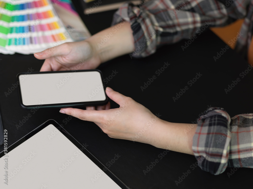 Female designer using mock up smartphone on black table with mock up tablet Female designer using mock up smartphone on black table with mock up tablet
