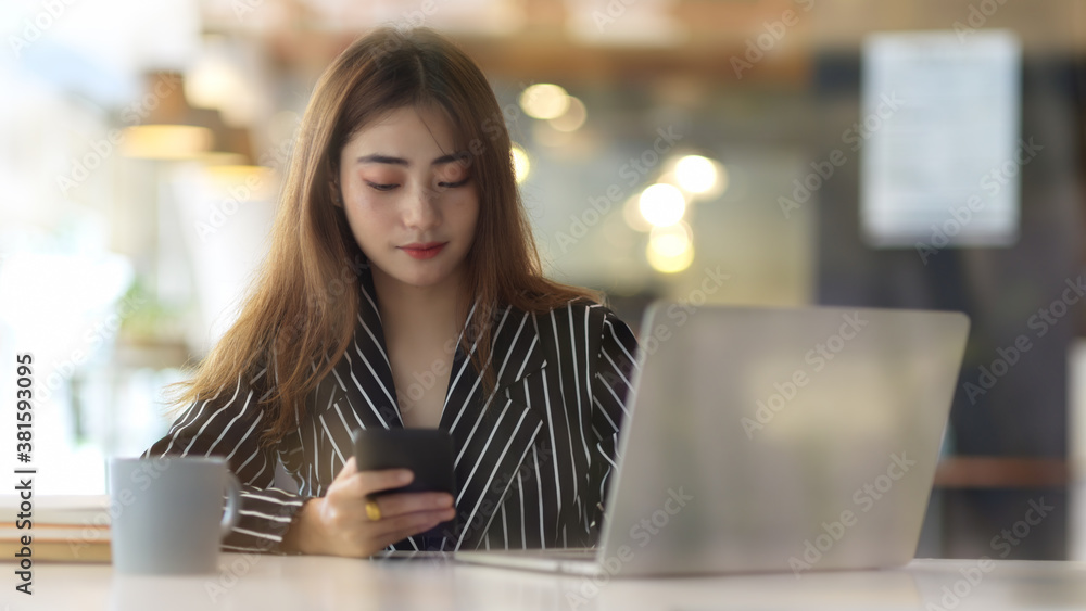 View through glass wall of female using smartphone in office room View through glass wall of female using smartphone in office room