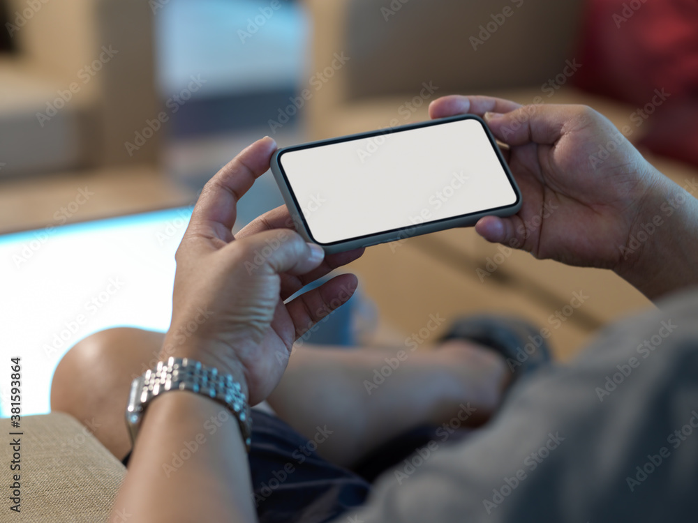 Male hands using mock up smartphone while relaxed sitting on couch