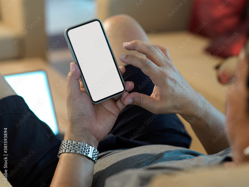 Male hands using mock up smartphone while relaxed sitting on couch Male hands using mock up smartphone while relaxed sitting on couch