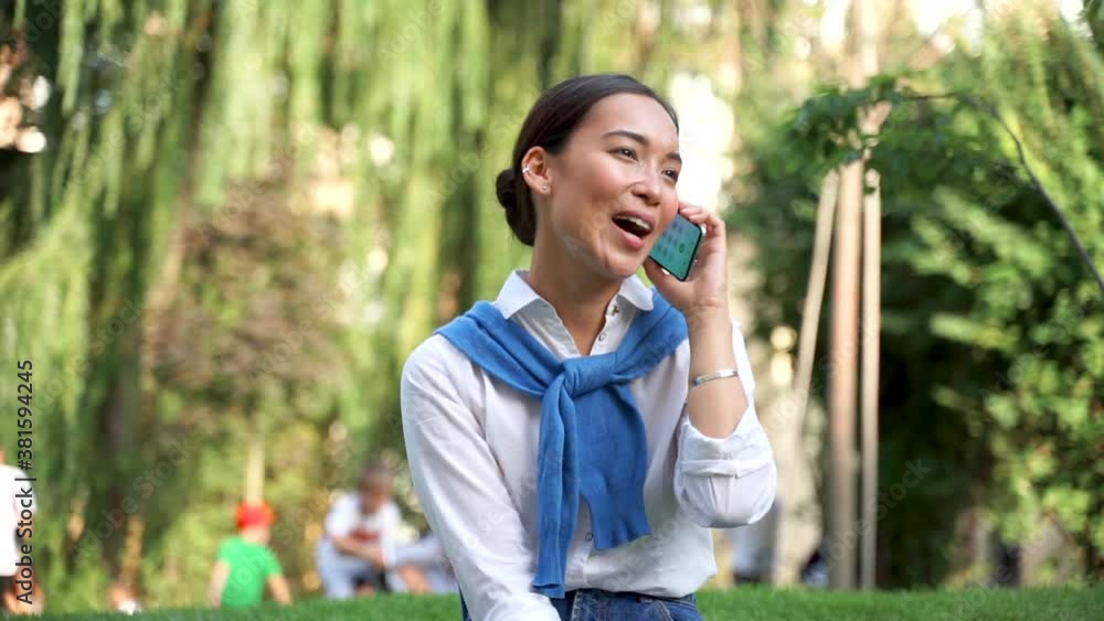 Asian woman talking on the phone outdoors. Medium shot. Asian woman talking on the phone outdoors. Medium shot.