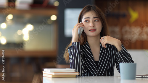 Female office worker talking on the phone while sitting at workplace