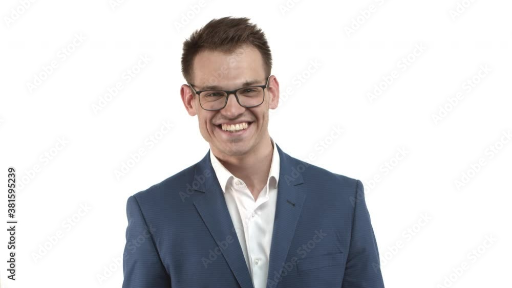 Young cheerful businessman in blue suit and glasses looking at camera with happy smile, standing over white background Young cheerful businessman in blue suit and glasses looking at camera with happy smile, standing over white background