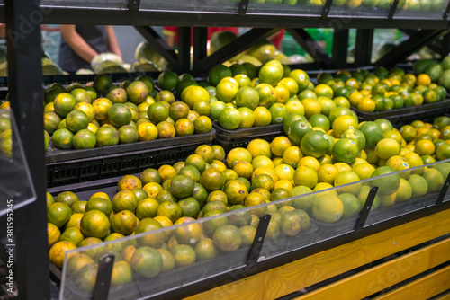 Fresh healthy fruits on shelves in supermarket. Green orange