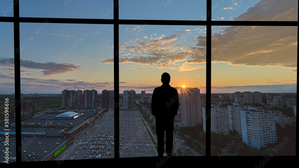 Fototapeta premium The man standing on the building against the city sunset