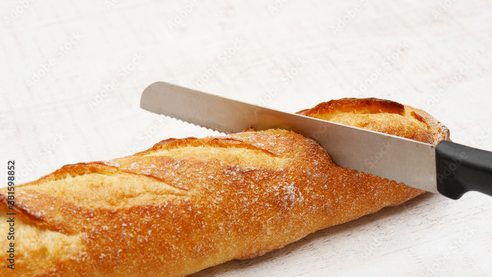 Obraz premium フランスパンをパンナイフで切る