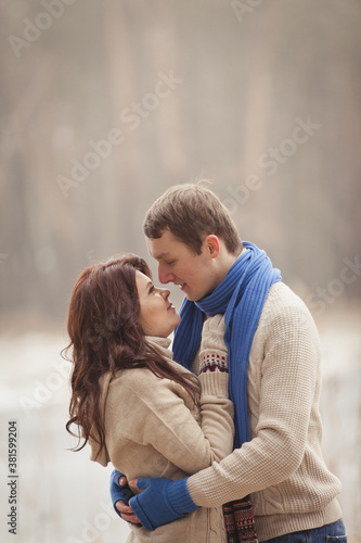 couple on winter walk in snow. Valentine's Day for couple in rustic style. Happy couple in love warming themselves with tea under a blanket in the arms of nature. Casual outfit with Blue accessories