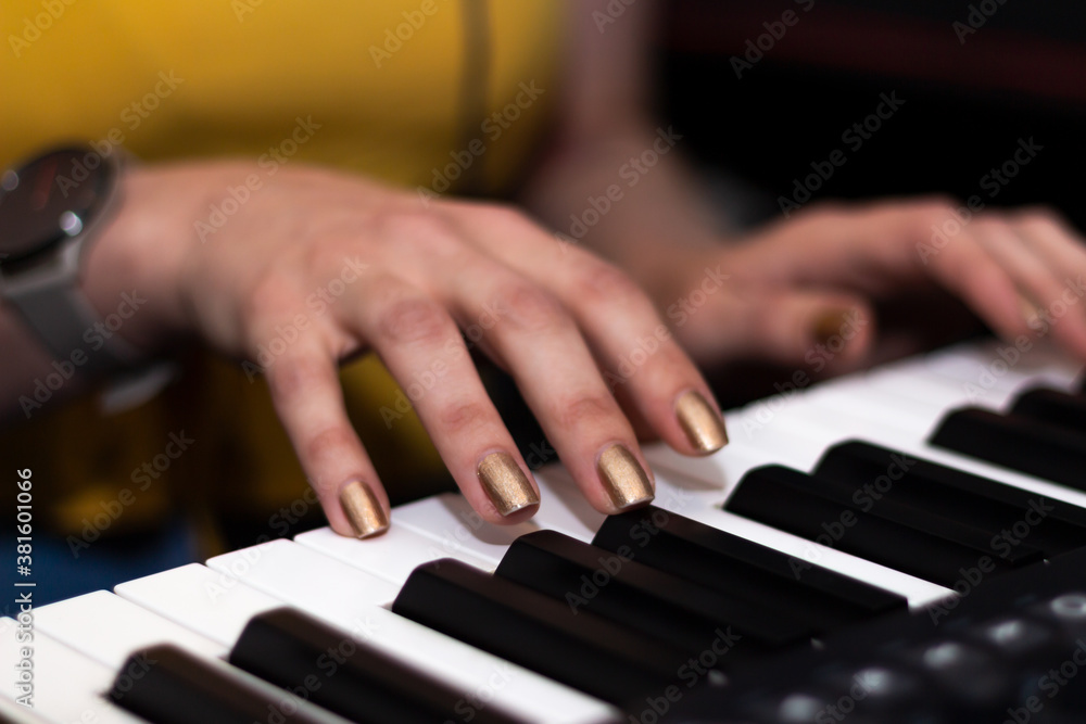 Obraz premium Girl Playing on a MIDI Keyboard with Golden Nails
