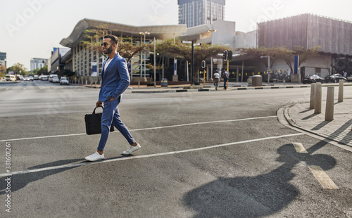 Trendy Indian Arabic businessman crossing city intersection