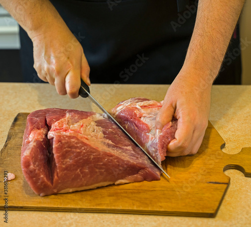 hands cut meat in the home kitchen