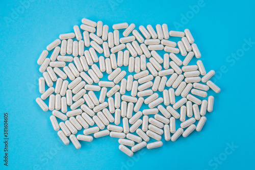 Light capsules are scattered on a blue background. The concept of vitamins, dietary supplements. Capsules in a white bottle, blue background. Copy space, minimalism, top view. Magnesium citrate.