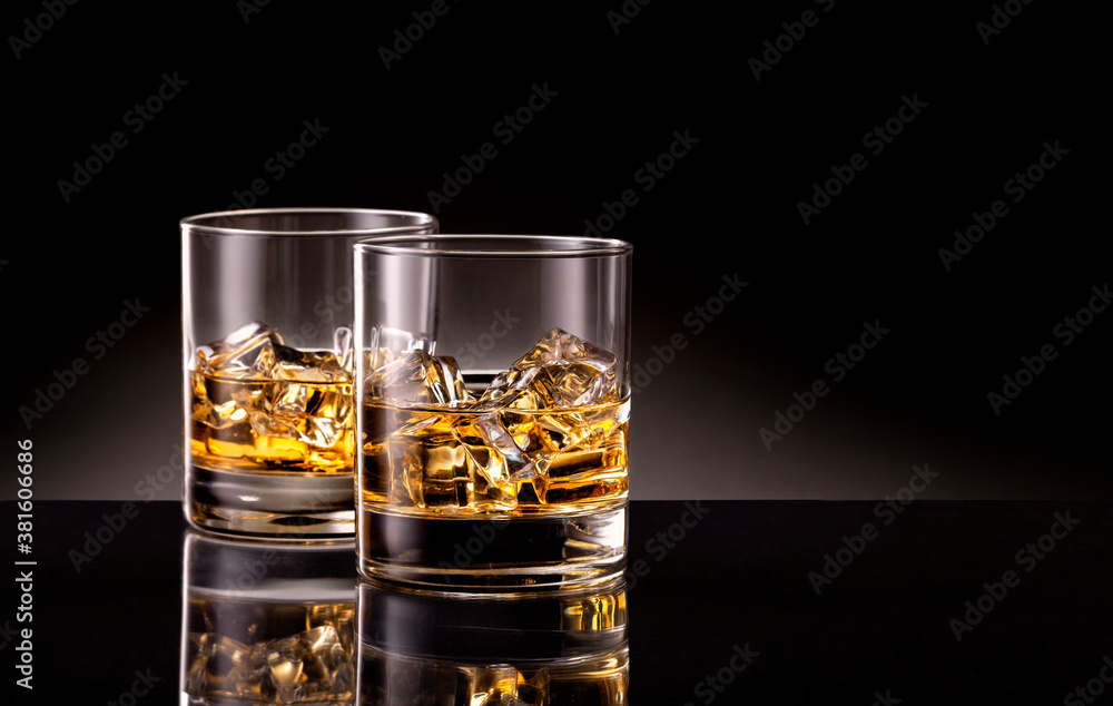 Two glasses of whiskey with ice cubes on black background. Two glasses of whiskey with ice cubes on black background.