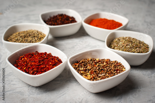  Spices in bowls on a gray concrete background.