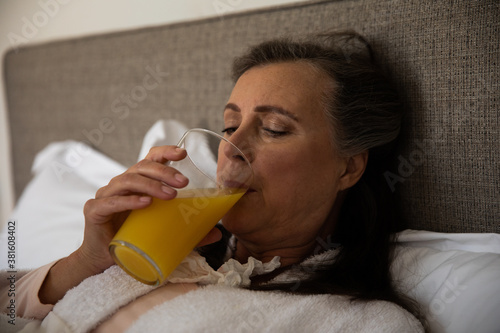 Senior woman drinking juice in bed at home