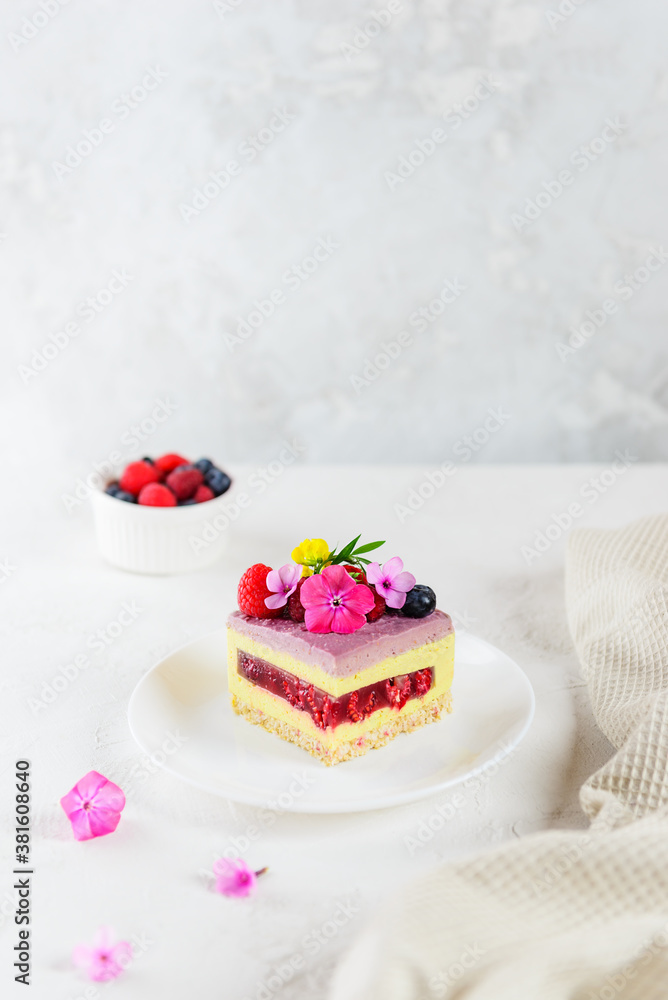 A piece of mousse raspberry lemon cake with raspberry jelly on a light background. Sugar, lactose and gluten free. A piece of mousse raspberry lemon cake with raspberry jelly on a light background. Sugar, lactose and gluten free.