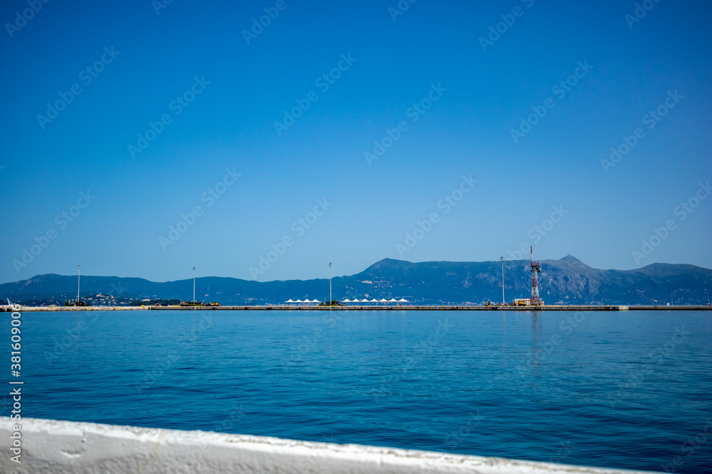 Entering the port of Kerkira. Corfu island, Greece. Classic blue color, mountains and sky in the background. Amazing sea landscape. Beautiful view from the ferry from Saranda, Albania