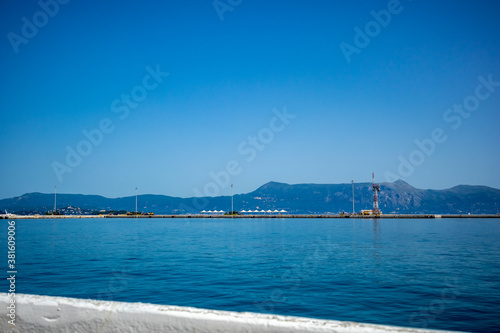 Fototapeta Naklejka Na Ścianę i Meble -  Entering the port of Kerkira. Corfu island, Greece. Classic blue color, mountains and sky in the background. Amazing sea landscape. Beautiful view from the ferry from Saranda, Albania