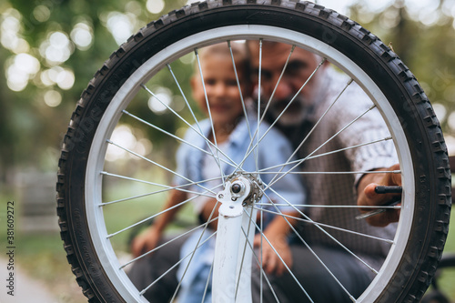 grandfather with his grandson at the city park fixing bicycle