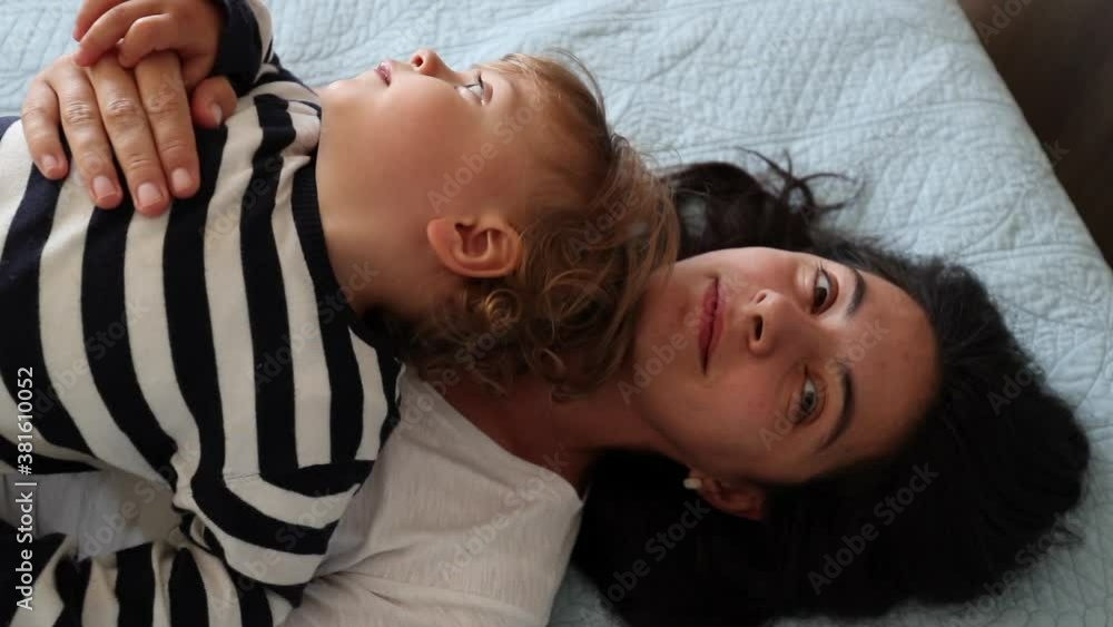 Mother and child toddler lying in bed together smiling at camera Mother and child toddler lying in bed together smiling at camera