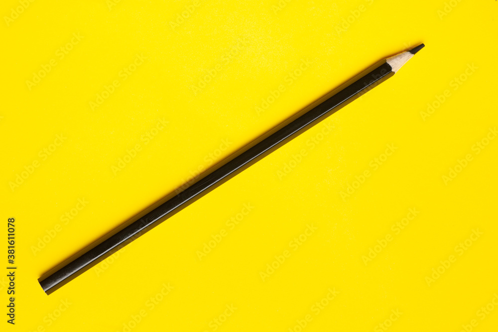 diagonal black sharp wooden pencil on a bright yellow background, isolated, copy space, mock up. diagonal black sharp wooden pencil on a bright yellow background, isolated, copy space, mock up.
