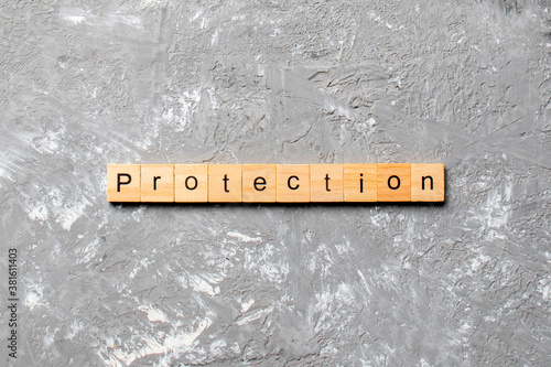PROTECTION word written on wood block. PROTECTION text on cement table for your desing, concept